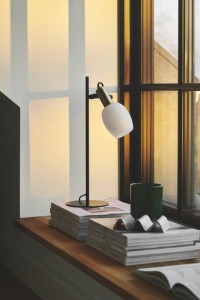 Lampa stołowa ARILD Nordlux 1xE14 40W Metal Czarny na parapecie, zapalona obok książek.