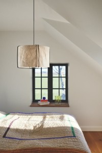 Lampa wisząca CARDINE Nordlux w białym papierowym abażurze nad łóżkiem w sypialni.