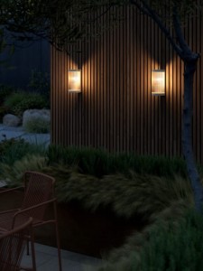 Lampa ścienna COUPAR Nordlux oświetlająca drewnianą ścianę ogrodu.