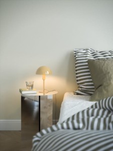 Lampa stołowa ELLEN Nordlux 1xE14 40W Metal Żółty na nocnym stoliku obok łóżka.