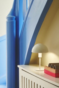 Lampa stołowa ELLEN Nordlux na białym biurku przy niebieskiej ścianie.