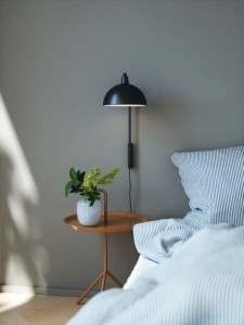 Lampa ścienna ELLEN Nordlux 1xE14 40W Metal Czarny zamontowana nad stolikiem nocnym w sypialni.