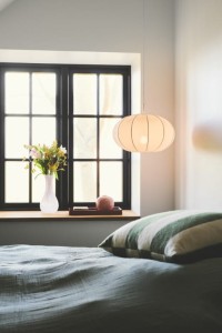 Lampa wisząca AERON Nordlux 1xE27 40W Tekstylia Biały nad parapetem z kwiatami.