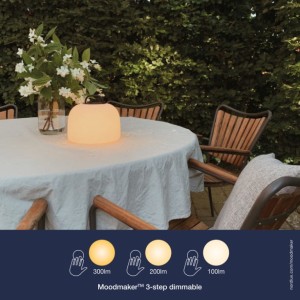Lampa na baterie KETTLE Nordlux 1xLED biała na stole w ogrodzie.