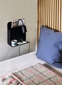 Lampa ścienna ROOMI Nordlux 1xGU10 35W Metal Czarny obok łóżka z fioletową poduszką, na półce książki i filiżanka.