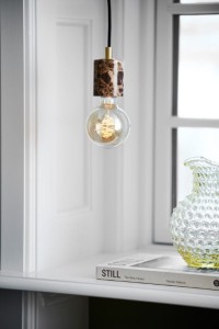 Lampa wisząca SIV Nordlux 1xE27 60W Marmur Brązowy nad książką i wazonem.
