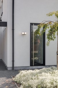 Kinkiet zewnętrzny LED Lutec Cuba zamontowany na białej ścianie.