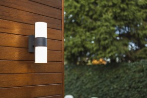 Kinkiet zewnętrzny LED Lutec Cyra 5198101118 IP54 zamontowany na drewnianej ścianie domu.