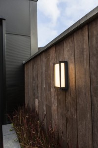 Kinkiet zewnętrzny LED Lutec Qubo 5193001118 zamontowany na drewnianym płocie.