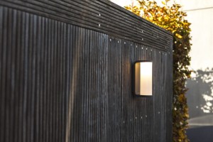 Kinkiet zewnętrzny LED Lutec Adalyn 5193602118 oświetlający drewnianą ścianę.