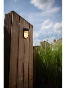 Kinkiet zewnętrzny LED Lutec Bullo 6383001118 zamocowany na drewnianym ogrodzeniu ogrodu.