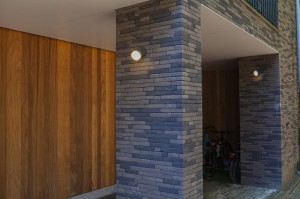 Kinkiet zewnętrzny LED Lutec Dropsi 5010901118 IP44 zamontowany na ceglanej ścianie budynku.