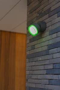 Kinkiet zewnętrzny LED Lutec Dropsi 5010901118 zamontowany na kamiennej ścianie.