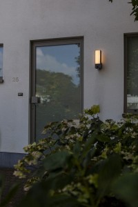 Kinkiet zewnętrzny LED Lutec Cuba Kamera 5193812118 zamontowany na ścianie budynku.