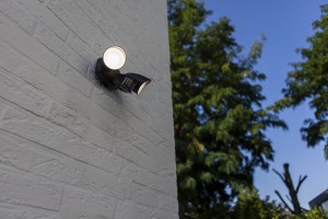 Kinkiet zewnętrzny LED Lutec Shrimp 7622221012 zainstalowany na białej ceglanej ścianie