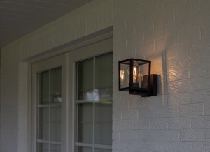 Lampa elewacyjna Lutec Shiva 5206501012 IP44 1xE27 Aluminium Czarny zamontowana na białej ścianie.