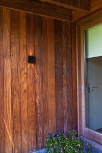 Kinkiet zewnętrzny LED Lutec Gemini 5104003012 IP54 1xLED Aluminium Czarny na drewnianej ścianie obok drzwi.