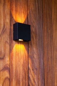 Kinkiet zewnętrzny LED Lutec Gemini 5104003012 zamontowany na drewnianej ścianie.