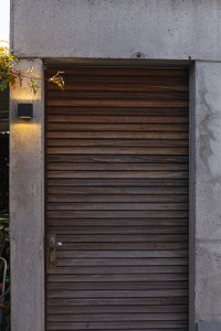 Kinkiet zewnętrzny LED Lutec Gemini 5189125012 IP54 na ścianie obok drewnianych drzwi.