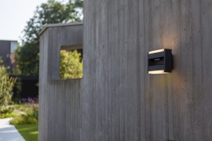 Kinkiet zewnętrzny LED Lutec Conroy 5107001118 zamontowany na betonowej ścianie.