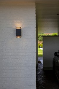 Nowoczesny kinkiet zewnętrzny Lutec Ridge 5107101118 zamontowany na białej ścianie.