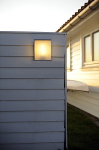 Lampa elewacyjna Elstead Lighting Torsten TORSTEN-TALL IP54 na ścianie domu w tle.