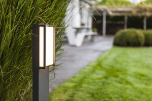 Słupek oświetleniowy Lutec Qubo 7193001118 IP54 1xLED Aluminium na tle ogrodu.