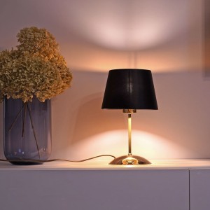 Lampka nocna GLORY TK Lighting 1xE27 15W Tkanina Czarno złoty na białym tle obok wazonu z suszonymi kwiatami.