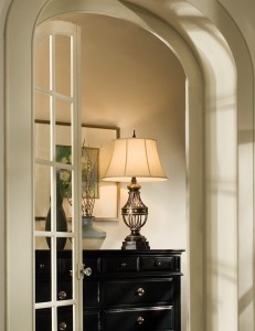 Lampa stojąca Augustine Elstead Lighting w kolorze brązowym na czarnej komodzie.