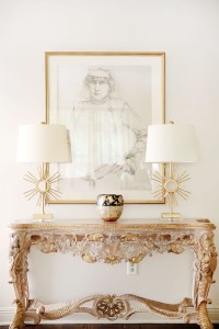 Lampa stojąca Sun King Elstead Lighting złotego koloru na ozdobnym stole.