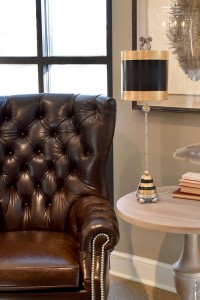 Lampa stojąca Phoenician Elstead Lighting 1x60W E27 Stal Czarny/Złoty obok skórzanego fotela w salonie.