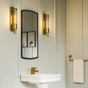 Lampa ścienna kinkiet Wellington Elstead Lighting w łazience na tle lustra i umywalki.