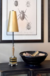 Lampa podłogowa Nettle Luxe Elstead Lighting w kolorze złota i beżu na tle grafiki z owadami.