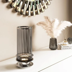 Lampa stołowa Arno Elstead Lighting z pryzmatycznego szkła, stalowy nikiel, na białej półce obok wazonu i dekoracji.